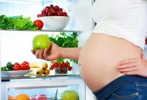 En gravid kvinne som holder et eple.
