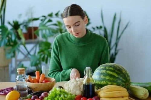 En kvinne omgitt av frukt og grønnsaker som inneholder A-vitamin.