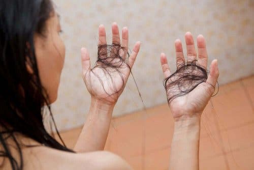 En kvinne som holder mistet hår i hendene sine