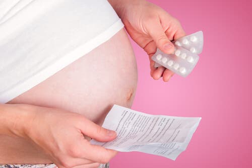 En gravid kvinne som holder piller