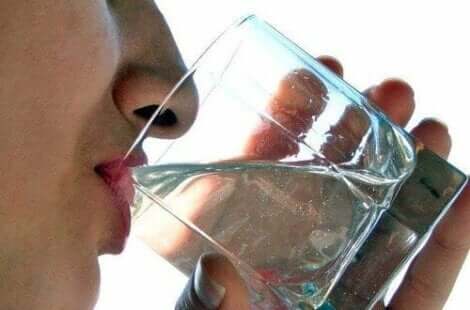 En kvinne som drikker et glass vann.