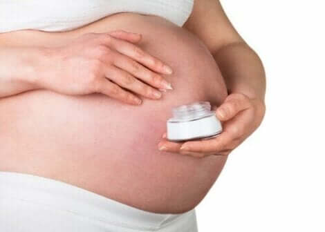 Gravid kvinne med en beholder med hudkrem.