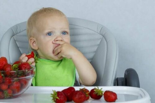 Baby som spiser jordbær.