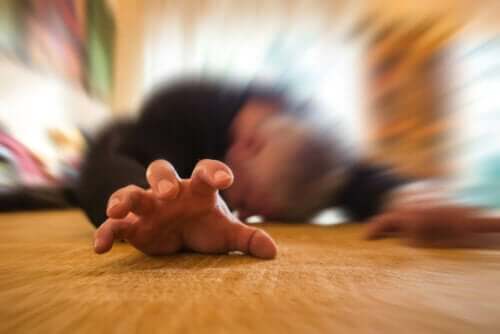 Mann på gulvet som opplever et epileptisk anfall