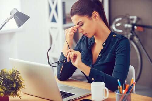 Kvinne på kontoret foran laptop står overfor daglig stress.