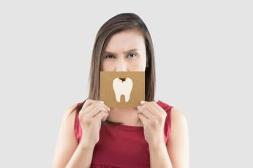 Kvinne som holder et skilt med en tann med et karies på foran munnen