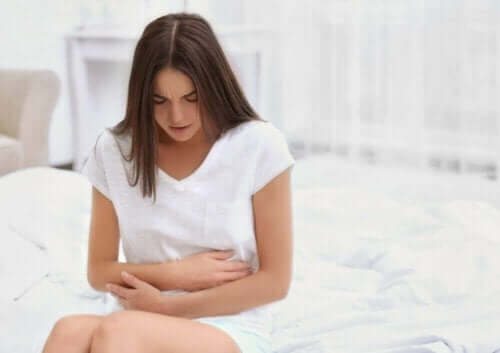 Kvinne med magesmerter i hvitt rom
