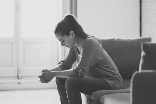 En trist kvinne som sitter på en sofa