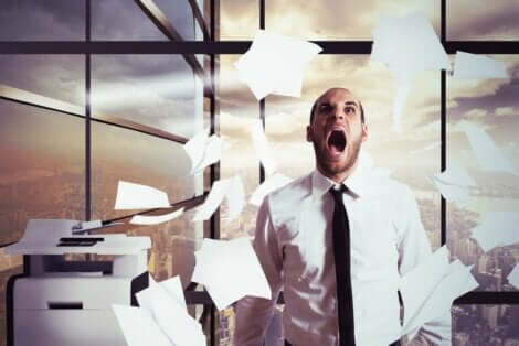 En mann som har et nervesammenbrudd på jobben og kaster papir i luften.