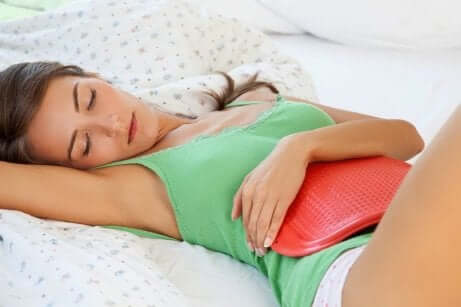 En kvinne med menstruasjonssmerter som bruker en varmepute.