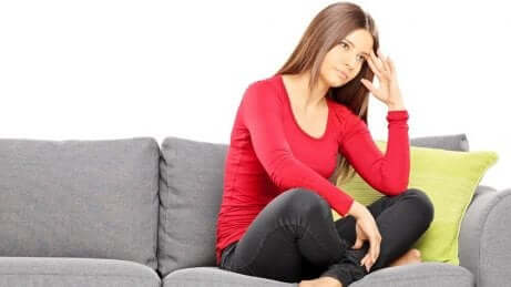 En kvinne som sitter på en sofa, opprørt.