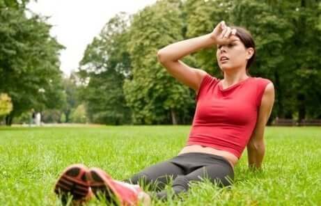 en kvinne som sitter på gresset etter trening