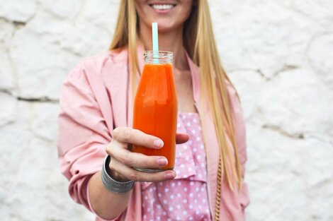 En kvinne som holder en gulrotjuice.