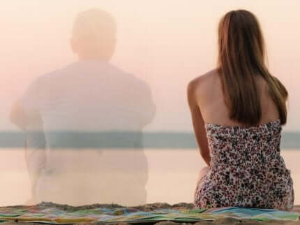 En kvinne som sitter på stranden med en mann som svinner hen.