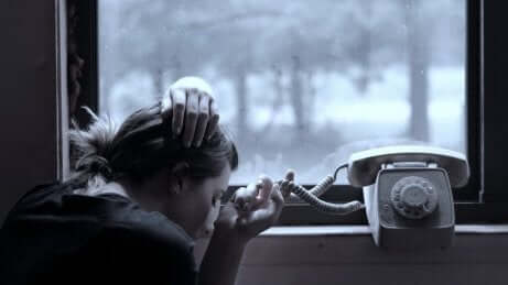 en kvinne som venter ved en telefon