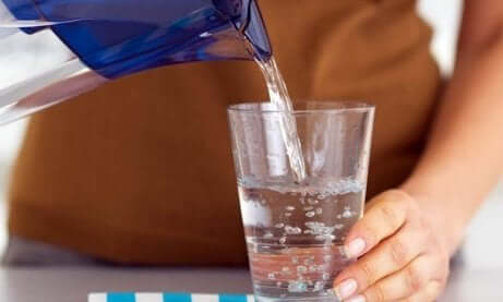 Tips for å unngå søvnighet på dagtid: vann blir servert i et glass