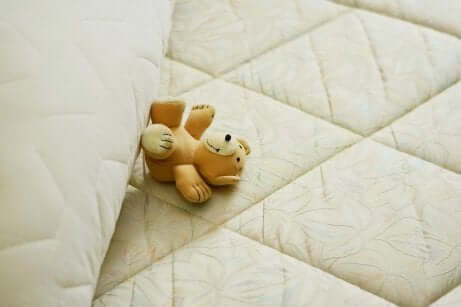 En bamse som ligger på en madrass