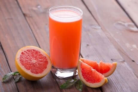 Et glass grapefruktjuice ved siden av en grapefrukt.