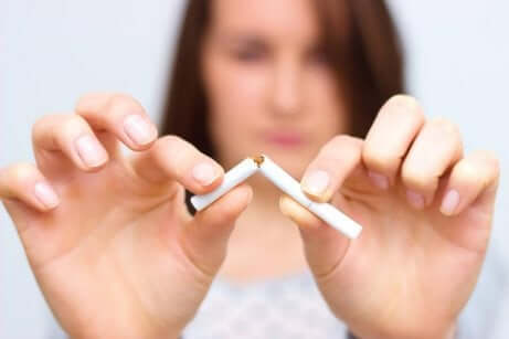 en kvinne som knekker en sigarett i to
