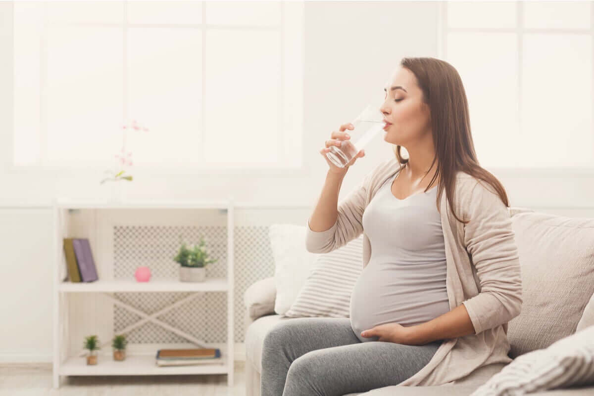 Gravid kvinne som drikker vann