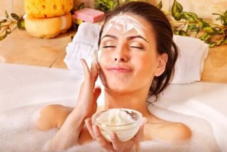 en kvinne som påfører ansiktsmaske i et badekar