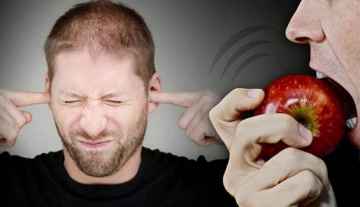 En mann irritert av noen som biter et eple som synger med lave serotoninnivåer
