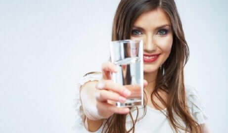 En kvinne som holder et glass vann