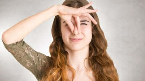 En kvinne som holder seg for nesen på grunn av en ubehagelig lukt.