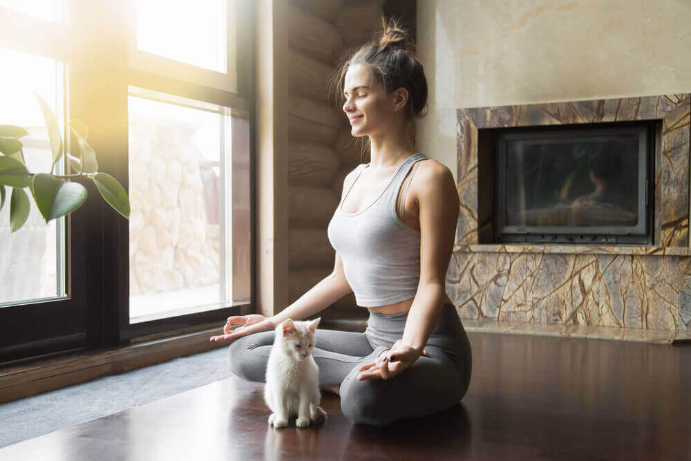 Kvinne i yogameditasjon med en katt