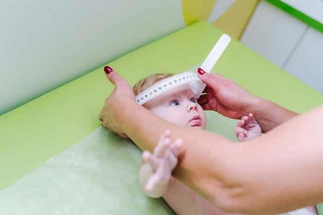 En barnelege som måler babyens kranium