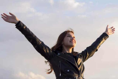 En ung kvinne som smiler med hendene i været.