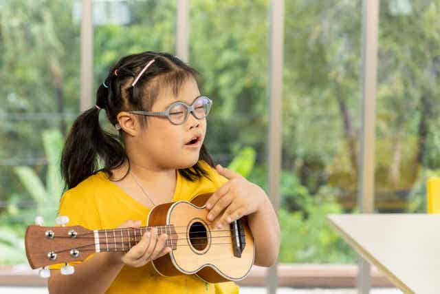 Et barn med Downs syndrom som spiller ukulele
