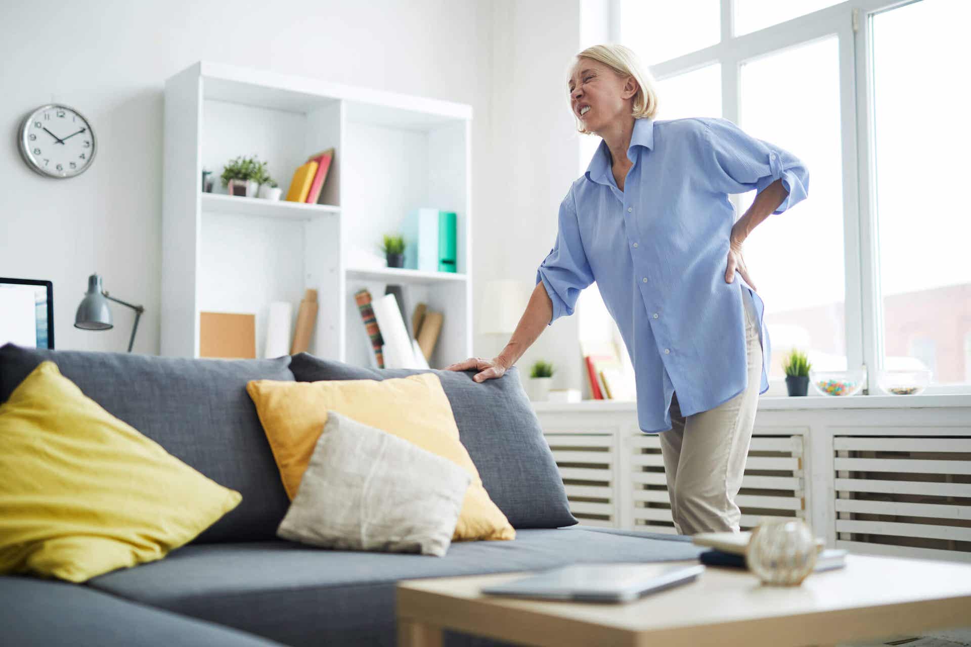 En kvinne som kryper sammen med hånden på korsryggen