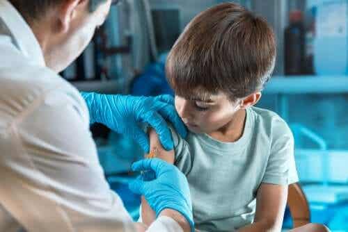 En lege som vaksinerer en ung gutt.