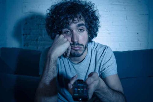 En mann som kjeder seg mens han ser på TV i mørket.