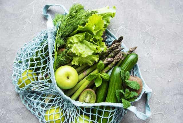 En pose full av grønne frukter og grønnsaker