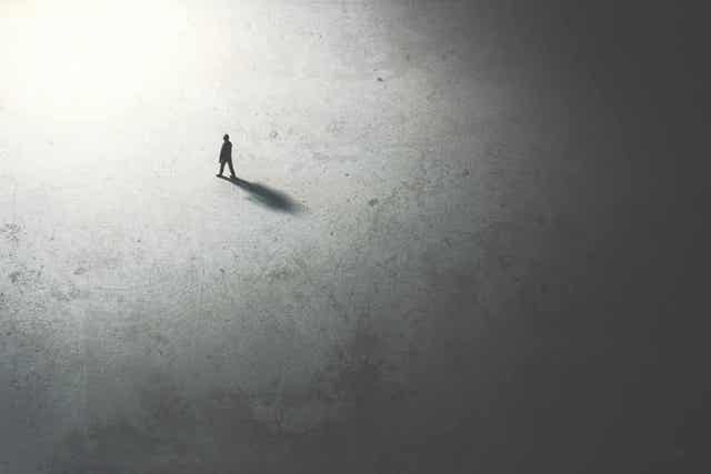 Silhuetten til en person som går fra mørke til lys