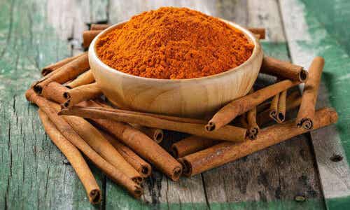 En bolle med malt kanel på et trebord med kanelstang