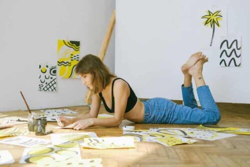 En kvinne som ligger på gulvet og maler alene.