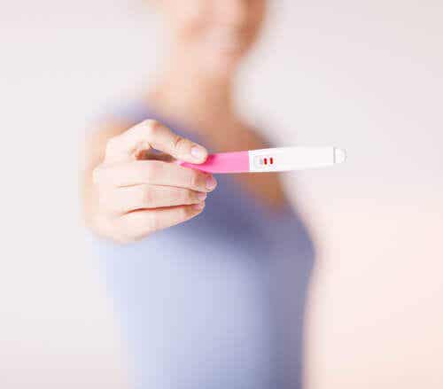 En kvinne som viser en positiv graviditetstest.