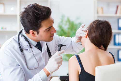 En lege som undersøker en kvinnes øre.