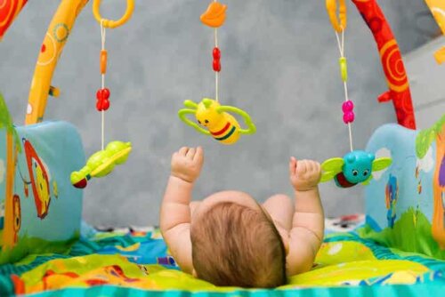 Et barn som ligger på ryggen og leker med et babygym.
